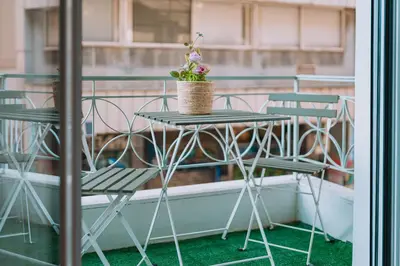 a table with chairs and a basket of flowers on a balcony at 4BED Apartment in the heart of Athens in Athens