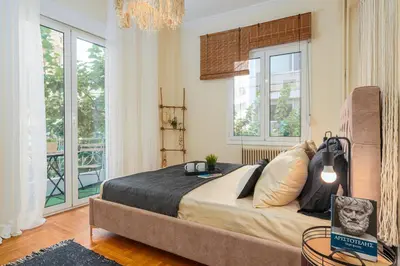 a bedroom with a large bed in a room with windows at 4BED Apartment in the heart of Athens in Athens