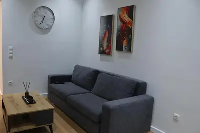 a living room with a couch and a clock on the wall at Golemis Apartments in Athens