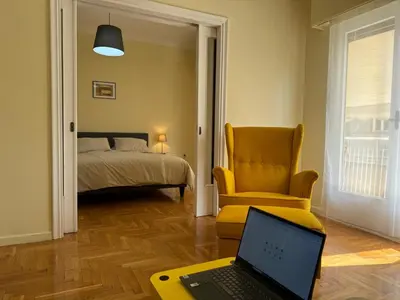 a room with a laptop and a chair and a bed at Cecilia's cozy flat in Athens