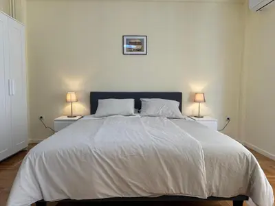a white bedroom with a large bed with two lamps at Cecilia's cozy flat in Athens