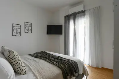 a white bedroom with a bed and a window at Serene City Hideaway with Balcony & Modern Comfort in Athens