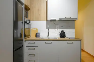 a kitchen with white cabinets and a stainless steel refrigerator at Serene City Hideaway with Balcony & Modern Comfort in Athens