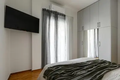 a bedroom with a bed and a flat screen tv at Serene City Hideaway with Balcony & Modern Comfort in Athens