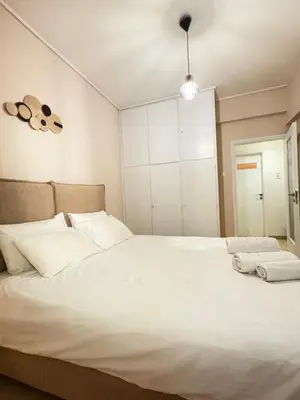 a bedroom with a large bed with white sheets at In the heart of Athens in Athens