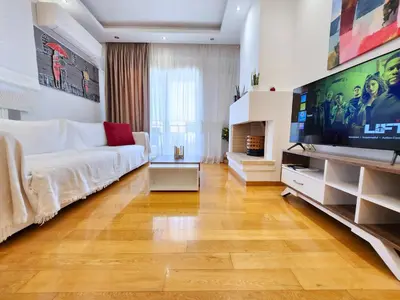 a living room with a white couch and a large tv at Tender Bliss in Athens