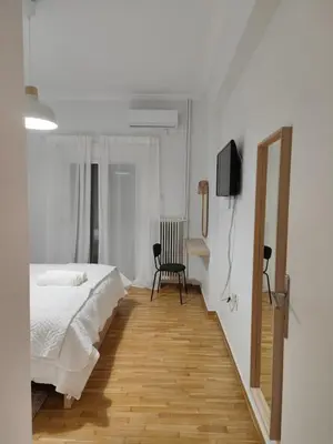 a white bedroom with a bed and a chair at Freshly Renovated Appartment in Athens