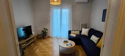 a living room with a blue couch and a tv at Freshly Renovated Appartment in Athens