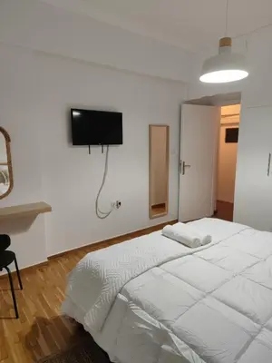 a bedroom with a white bed and a tv on the wall at Freshly Renovated Appartment in Athens