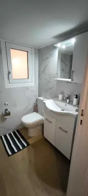 a white bathroom with a toilet and a sink at Freshly Renovated Appartment in Athens