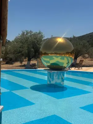 a swimming pool with a large metal ball on top of it at Seven stars Camping Evelina in Keratea