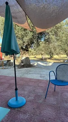 a green umbrella sitting next to a chair and a table and chair at Seven stars Camping Evelina in Keratea