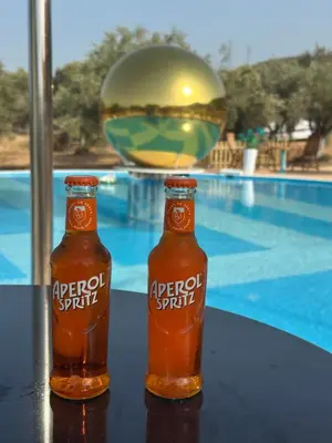 two bottles of beer sitting on a table next to a pool at Seven stars Camping Evelina in Keratea