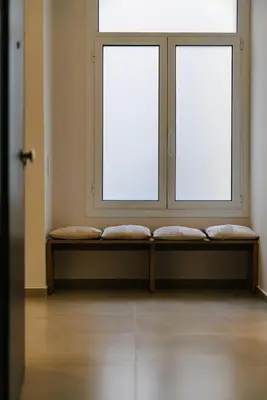 two windows in a room with a bench in front at Y Residence in Athens