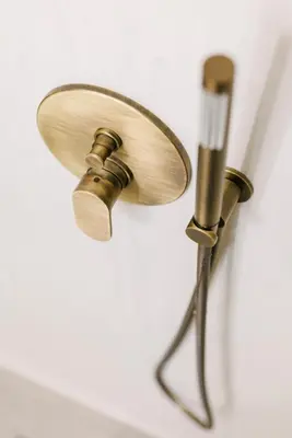 a brass shower head on a white wall at Y Residence in Athens