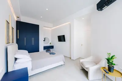 a white bedroom with a bed and a chair at Y Residence in Athens