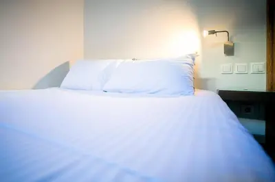 a bed with white sheets and pillows in a room at The studio in the heart of Athens-Plaka in Athens