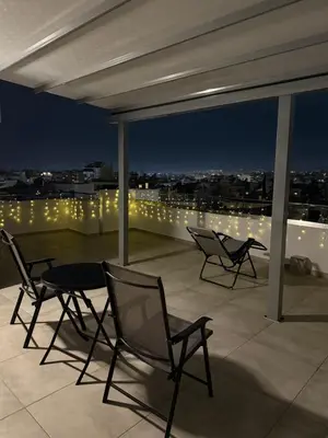 two chairs and a table on a balcony at night at M&H and their friends B in Athens