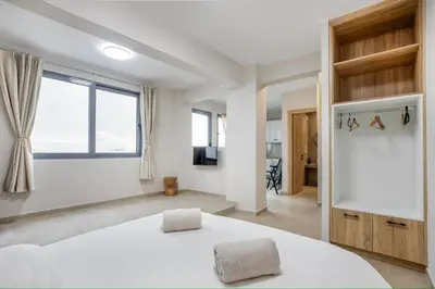 a bedroom with a white bed and a large window at M&H and their friends B in Athens