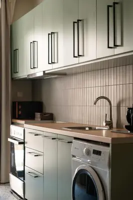 a kitchen with white cabinets and a washing machine at The Verve by Zoia Living in Athens