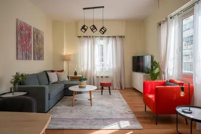 a living room with a blue couch and red chairs at Mia Homes - Heart of Athens in Athens