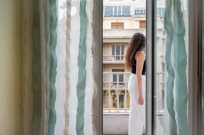a woman is looking out of a window at Mia Homes - Heart of Athens in Athens