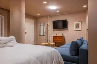 a bedroom with a bed and a blue couch and a tv at Lux Downtown Kolonaki in Athens