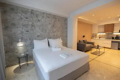 a bedroom with a large white bed and a living room at Belle Athenes Apartements in Athens
