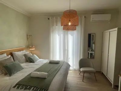 a bedroom with a bed with a chair and a window at Athenian Boho Nest by 8essentially in Athens