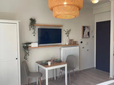 a dining room with a table and chairs and a tv at Athenian Boho Nest by 8essentially in Athens