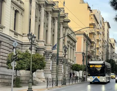 a bus driving down a street in front of a building at Athenian Boho Nest by 8essentially in Athens