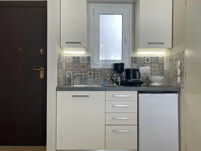 a kitchen with white cabinets and a sink at Athenian Boho Nest by 8essentially in Athens