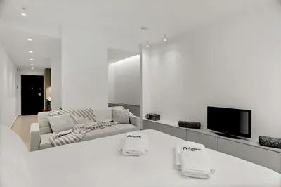 a white living room with a couch and a tv at Athenian Harmony Parliament Square Athens Centre in Athens