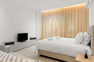 a white bedroom with a large bed and a tv at Athenian Harmony Parliament Square Athens Centre in Athens