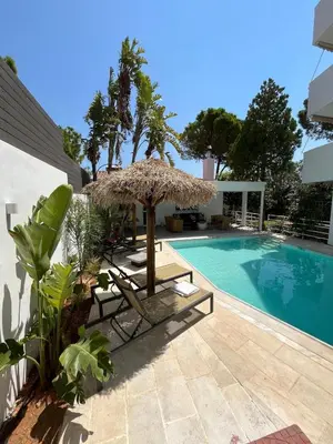a swimming pool with chairs and an umbrella next to a swimming pool at El Mar, Pool House with 3 BDR, 7 min from beach in Saronida