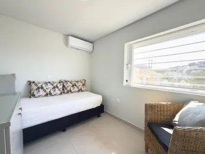 a small bedroom with a bed and a window at El Mar, Pool House with 3 BDR, 7 min from beach in Saronida