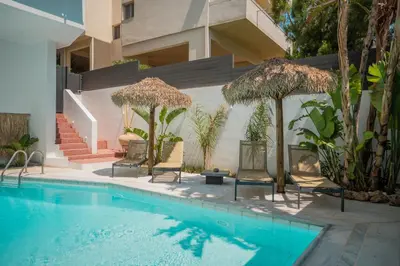 a swimming pool with chairs and umbrellas next to a building at El Mar, Pool House with 3 BDR, 7 min from beach in Saronida