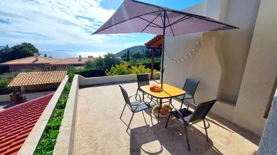a table and chairs with an umbrella on a patio at Summer Breeze villa in Saronic Gulf in Anavissos