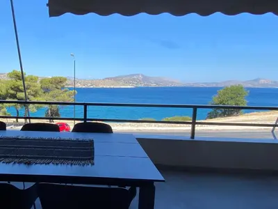 a table with chairs and a view of the water at Beachfront Apartment in Varkiza in Vari