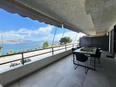 a dining room with a view of the ocean at Beachfront Apartment in Varkiza in Vari