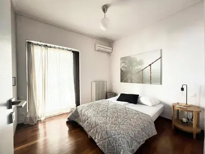 a bedroom with a bed and a large window at Beachfront Apartment in Varkiza in Vari