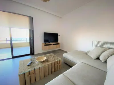 a living room with a couch and a tv at Beachfront Apartment in Varkiza in Vari