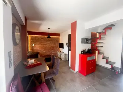 a living room with a table and chairs and a staircase at Metaxourgio Apartments in Athens
