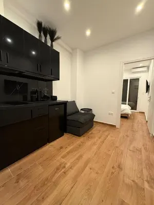a living room with a black kitchen and wooden floors at ATH Lux apartment in Athens