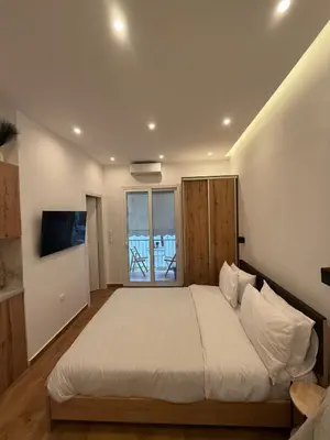 a bedroom with a large white bed and a television at ATH Cozy Studio in Athens