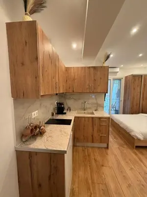 a kitchen with wooden cabinets and a bed in a room at ATH Cozy Studio in Athens