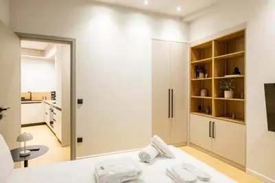 a bedroom with a white bed and a kitchen at Rooms151 Smart Suite in the Center of Athens 1st floor-2S in Athens