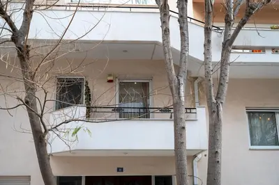 a white building with two windows and two trees at Apartment near Acropolis in Athens