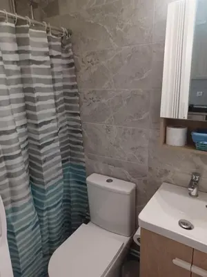 a bathroom with a toilet and a shower curtain at relax studio appartment in Porto Rafti