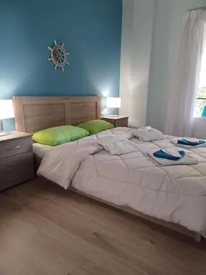 a bedroom with a large bed with a blue wall at relax studio appartment in Porto Rafti